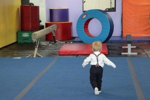 a toddled running towards a large foam circle in a gymnastics studio.